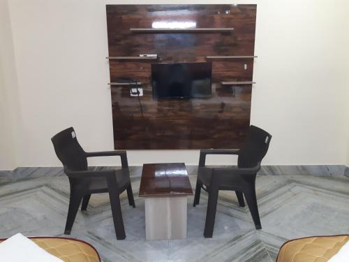 two chairs and a table in a room with a tv at Devansh Bhanu Residency DBR in Srikalahasti