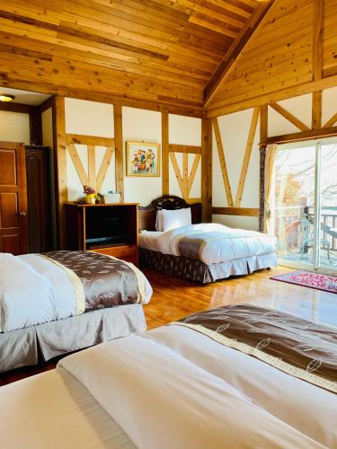 a bedroom with three beds in a room with wooden ceilings at The Cotswolds Villa in Renai