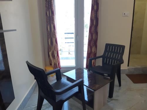 two chairs and a table in front of a window at Devansh Bhanu Residency DBR in Srikalahasti