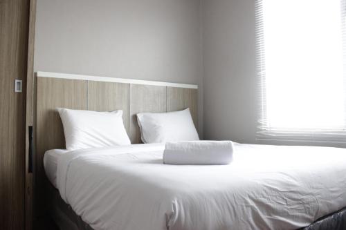 una camera da letto con un grande letto bianco con una finestra di Simply 1BR Apartment at Stanford Jatinangor By Travelio a Sayang