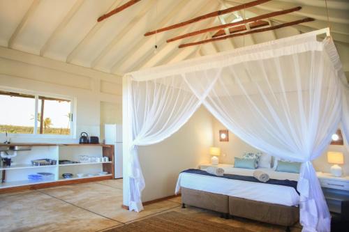 a bedroom with a bed with a canopy at Musica do Mar Beach Front Apartments, Ocean View in Praia do Tofo