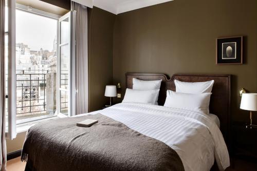 ein Schlafzimmer mit einem großen Bett und einem großen Fenster in der Unterkunft Hotel Rochechouart - Orso Hotels in Paris