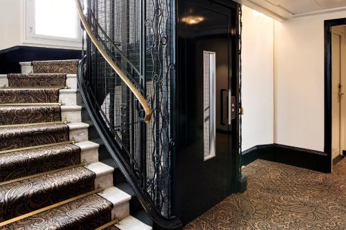a hallway with a black door and a staircase withoren carpet at Hotel Rochechouart - Orso Hotels in Paris