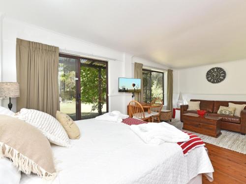 a bedroom with a large white bed and a living room at Olive Grove 1 Studio in Pokolbin