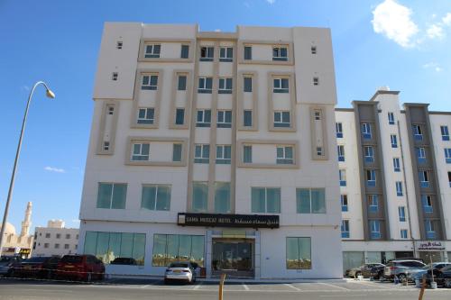 a large building with cars parked in a parking lot at Sama Muscat Hotel in Al Khawḑ