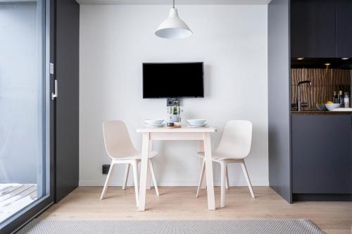 a white dining room table with white chairs and a tv at HOOM Home & Hotel Järfälla in Järfälla