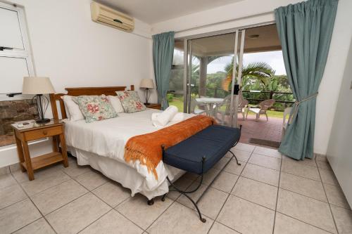 1 dormitorio con cama, mesa y ventana en Laguna La Crete 87 en Uvongo Beach