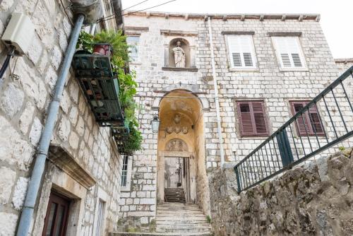 um antigo edifício de pedra com uma escada que leva a uma porta em La Porta Heritage em Dubrovnik