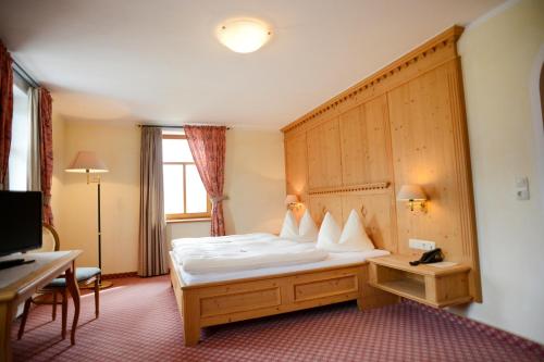 una camera d'albergo con letto e testiera in legno di Alpengasthof zur Post a Schattwald