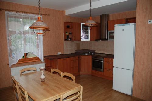 kuchnia z drewnianym stołem i białą lodówką w obiekcie Amber Cottage w Jurmale