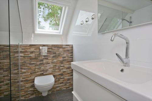 een badkamer met een toilet, een wastafel en een raam bij Jonkerstee 66 - Ouddorp De vrolijke noot Childfriendly near the beach - not for companies in Ouddorp