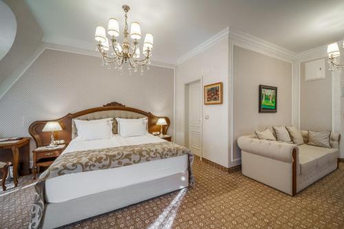 a bedroom with a bed and a couch and a chandelier at Residence City Garden - Certificate of Excellence Top 10 BEST Five-Stars City Hotels for 2024 awarded by HTIF in Plovdiv