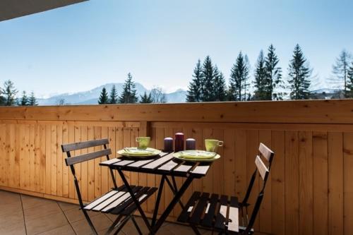 une table et des chaises sur une terrasse avec une clôture dans l'établissement Komfortowe apartamenty u stóp Giewontu, à Kościelisko