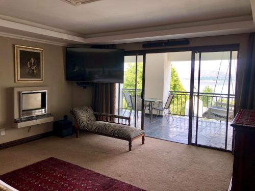 salon z kanapą i telewizorem oraz balkonem w obiekcie Kosmos Lodge w mieście Hartbeespoort