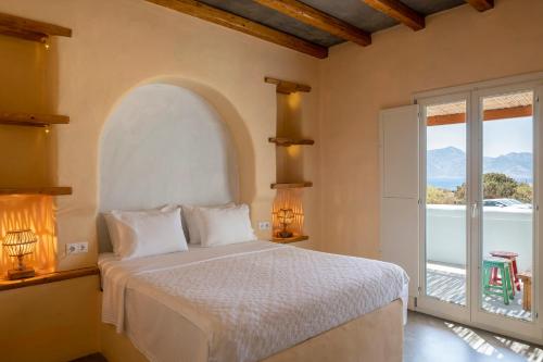 a bedroom with a bed and a large window at Pangaia Seaside Ηotel Adults Only in Koufonisia