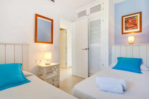 a bedroom with two beds and a mirror at APARTAMENTOS SON BOU Z5 in Son Bou