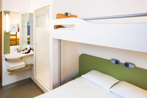 a small room with a bed and a mirror at ibis budget London Hounslow in Hounslow