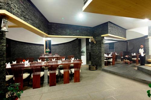 a restaurant with a long table and chairs and a man at Manuallaya The Resort & Spa in Manāli