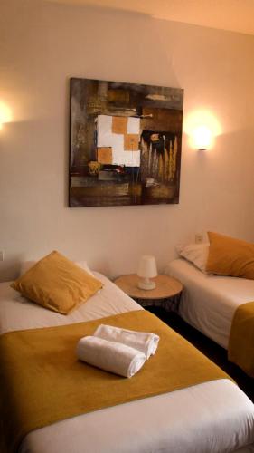 カンペールにあるホテル ル ダービーのベッド2台が備わる客室で、壁には絵画が飾られています。