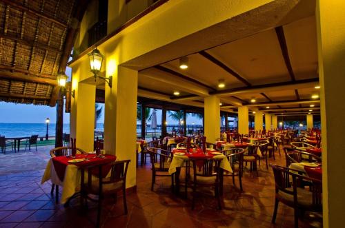 a restaurant on the beach with tables and chairs at White Sands Hotel in Dar es Salaam