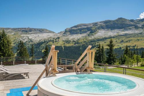 un bain à remous sur une terrasse avec des montagnes en arrière-plan dans l'établissement Résidence Pierre & Vacances Premium Les Terrasses d'Hélios, à Flaine