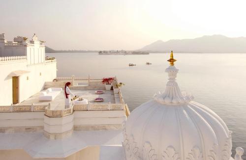 a woman standing on the edge of a building overlooking the water at Taj Lake Palace Udaipur in Udaipur