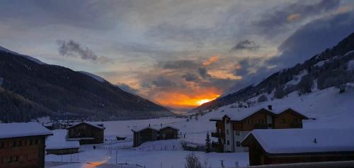 a village in the snow with the sunset in the background at Chalet Breithorn- Perfect for Holiday with Amazing View! in Obergesteln