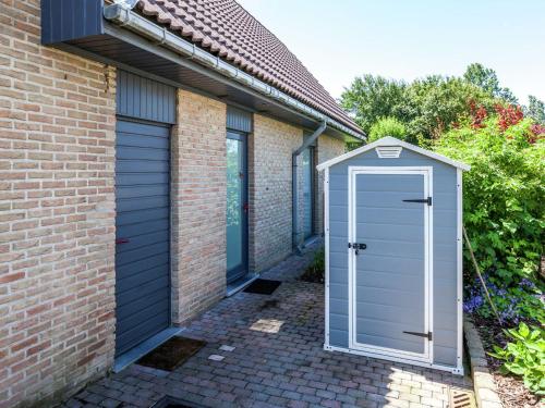 a blue garage door on the side of a brick house at Holiday Home in Bredene Terrace Fenced Garden in Bredene