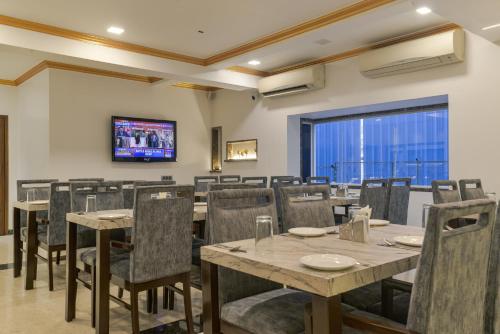a dining room with tables and chairs and a tv at Hotel Airlink in Mumbai