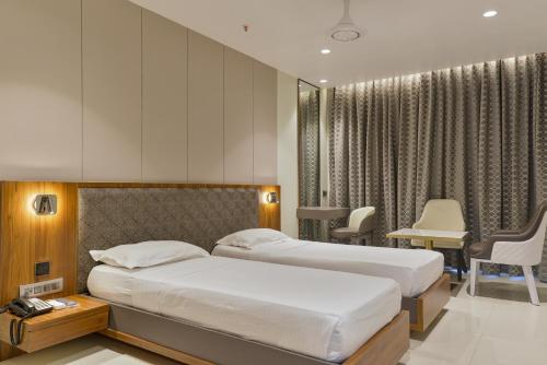 a bedroom with two beds and a table and chairs at Hotel Airlink in Mumbai