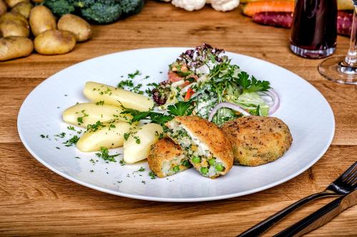 a white plate of food with a salad and vegetables at Hotel Neuwarft in Dagebüll