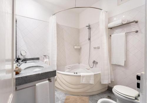 a white bathroom with a tub and a toilet and a sink at ALTIDO Bairro Alto Design in Lisbon