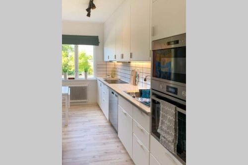 a kitchen with white cabinets and a stove top oven at Toppmodern familjelägenhet nära Kalmar slott och långviksbadet in Kalmar