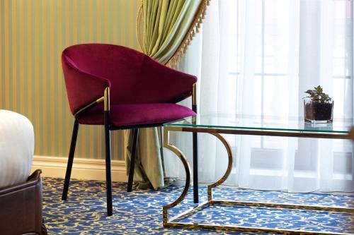 a red chair sitting next to a glass table at Envy Hotel in Durrës