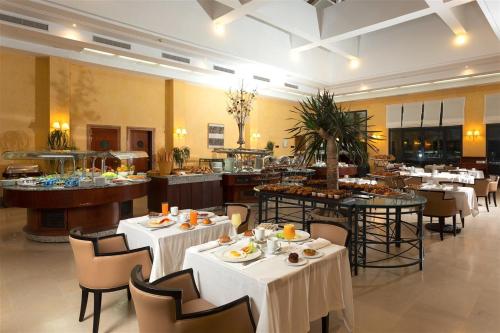 een restaurant met witte tafels en stoelen en een buffet bij Concorde Les Berges du Lac in Tunis