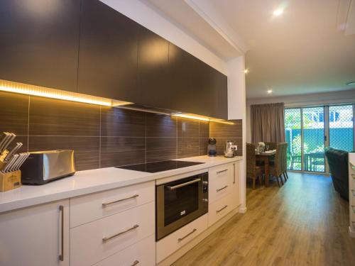 una cocina con armarios blancos y electrodomésticos negros en Broadwater Paradise, en Gold Coast