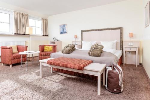 SimonsbergにあるHotel und Spa Lundenbergsandのベッド1台と椅子2脚が備わるホテルルームです。