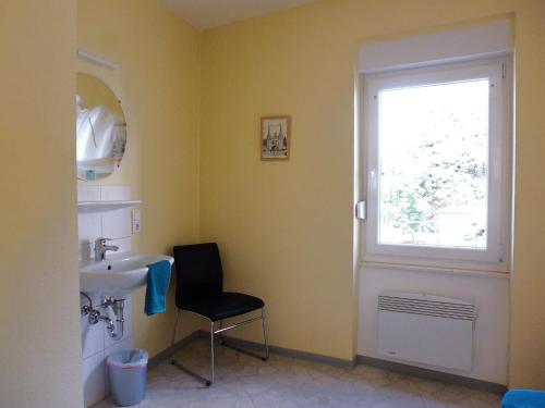 łazienka z umywalką, oknem i krzesłem w obiekcie Ferienhaus Alte Mühle w mieście Zell an der Mosel
