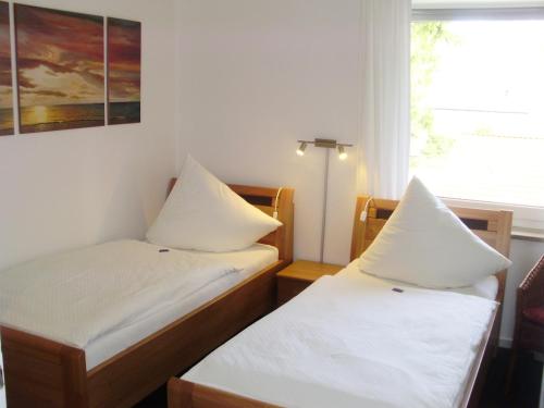 two beds in a small room with a window at Hotel Garni Waldsegler in Bad Sachsa