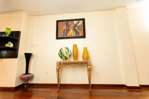 a table with vases and a painting on a wall at Best Western Premier Accra Airport Hotel in Accra
