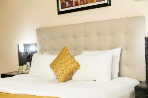 a bedroom with a white bed with a yellow pillow at Best Western Premier Accra Airport Hotel in Accra