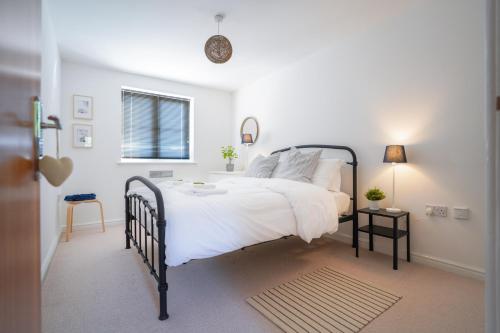 een slaapkamer met een bed met witte lakens en een raam bij Stylish Apartment with Private Parking in Cardiff
