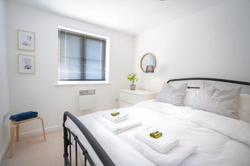 a white bedroom with a large white bed with two towels at Stylish Apartment with Private Parking in Cardiff