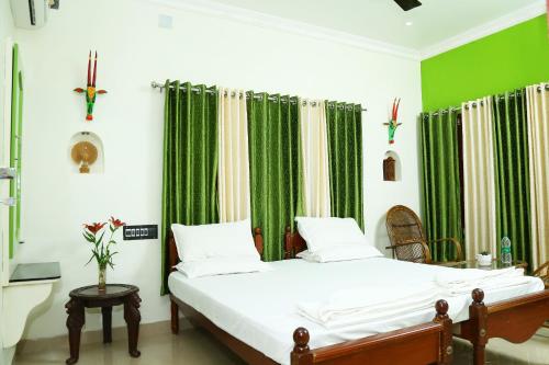 1 dormitorio con 1 cama con cortinas verdes en Jasmin Villa, en Kochi