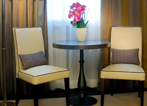 dwa krzesła i stół z wazonem kwiatów w obiekcie Holiday Inn Rome - Eur Parco Dei Medici by IHG w Rzymie