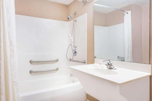 Super 8 by Wyndham Greer/Spartanburg Area في غرير: حمام أبيض مع حوض ودش