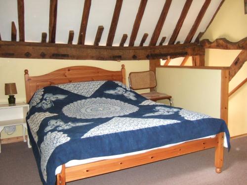 a bedroom with a wooden bed with a blue comforter at Snooky's Barn at Brook Cottage in Graffham