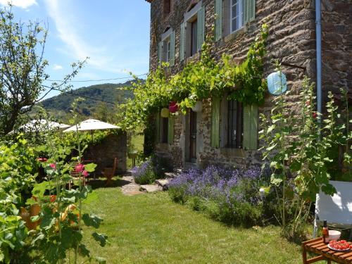 a garden outside a stone house with flowers at Holiday home in the forest in Auzat