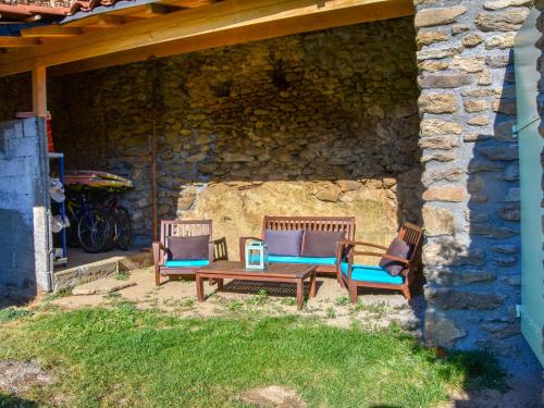 drie stoelen en een tafel voor een stenen muur bij Holiday home in the forest in Auzat