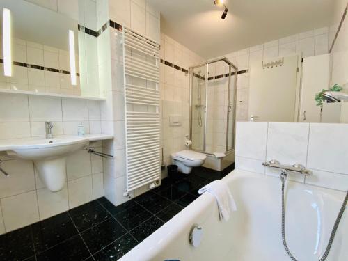 a bathroom with a tub and a sink and a toilet at Haus Sabine - Ferienwohnung Mine in Ahlbeck